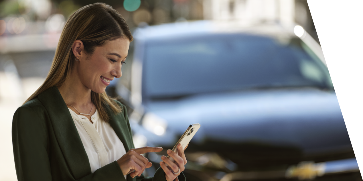 A Lady Using Her Phone with a Chevy Vehicle Behind Her