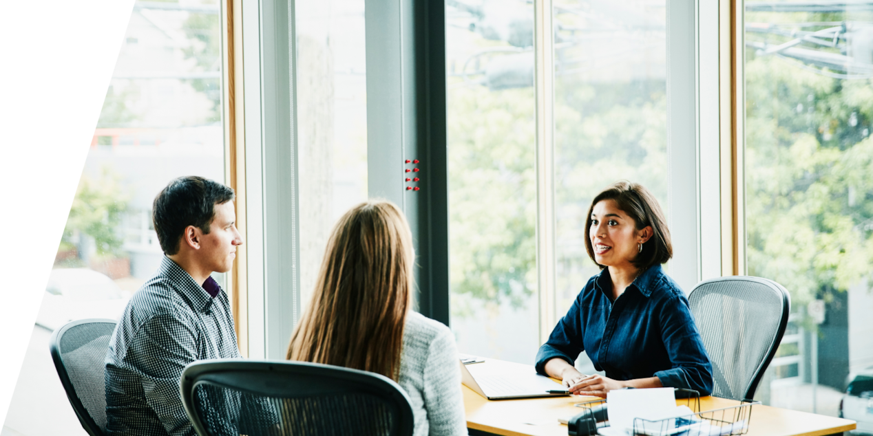 A Couple Talking to a Lady Sitting at a Desk