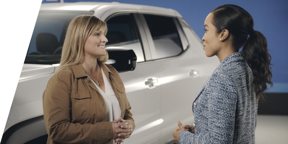 Two People Standing Next a Chevrolet Silverado EV Truck Having a Conversation