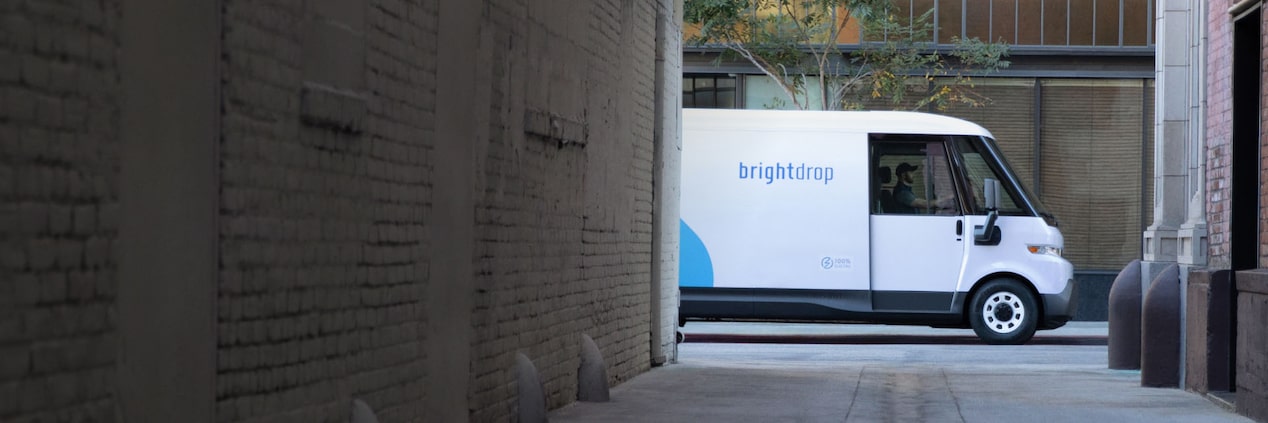 The side of a Brightdrop electric van viewed from an alley.