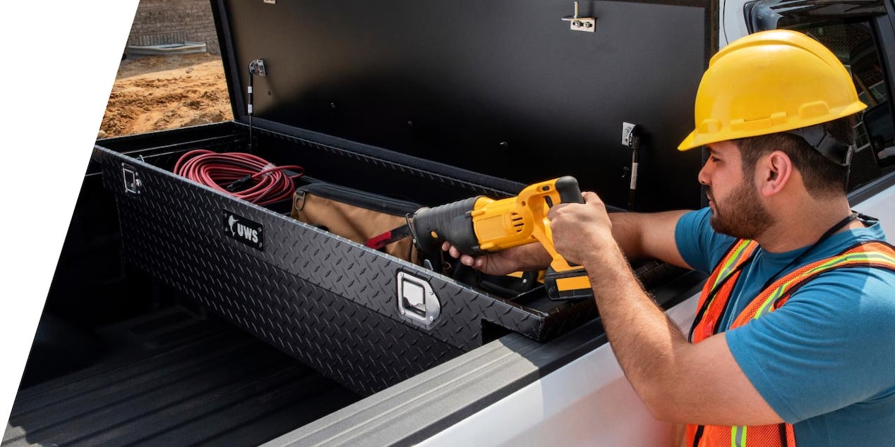 a worker storing tools in their truck bed tool box