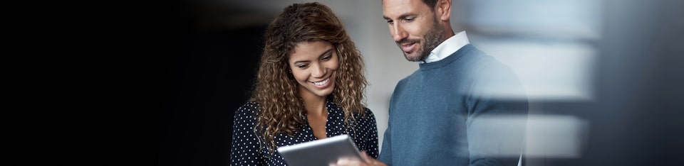 Two Smiling People Looking Down at a Tablet