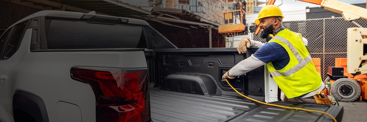 A worker using the outlet in their GM Truckbed. 