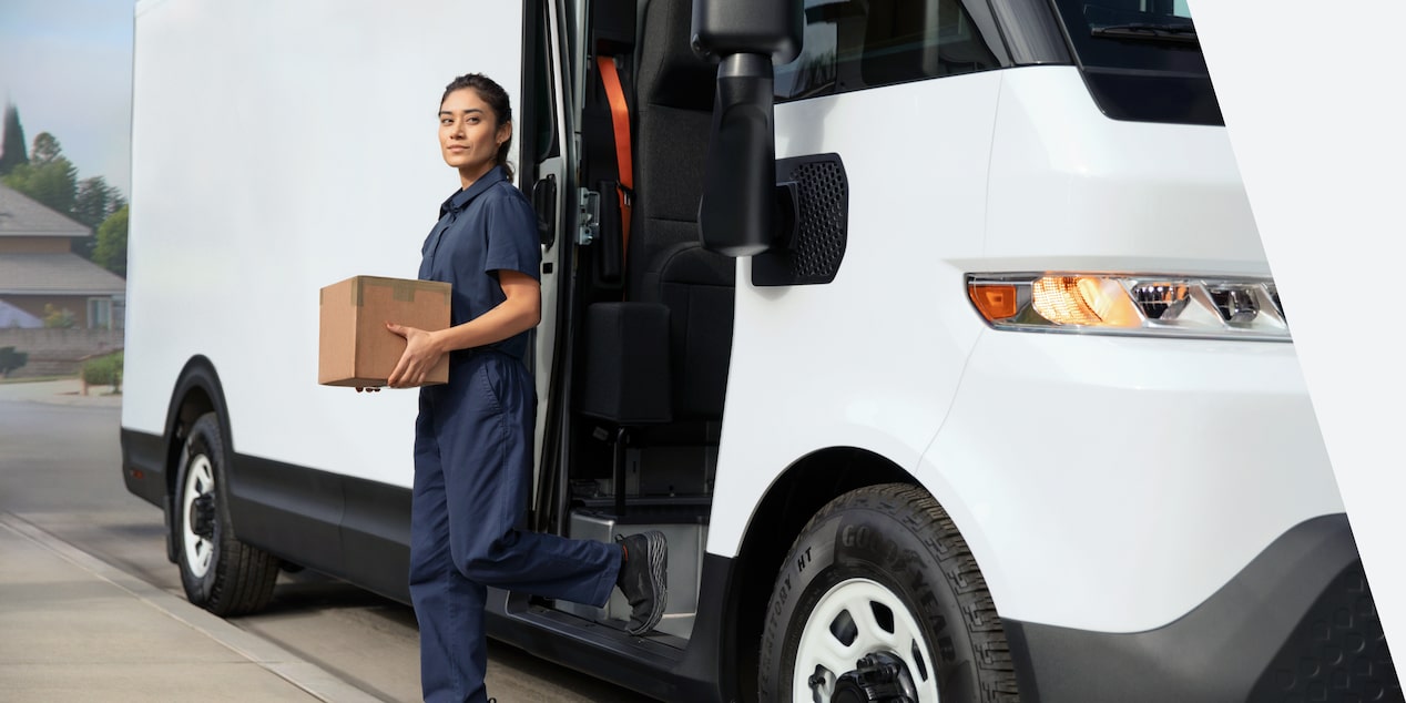 An exterior closeup view of a woman holding a package outside of the 2024 Chevrolet Brightdrop