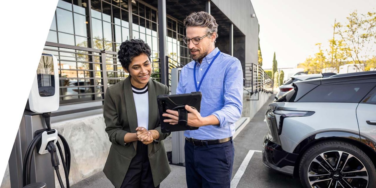 two people standing by a 2024 blazer EV parked next to a charging station