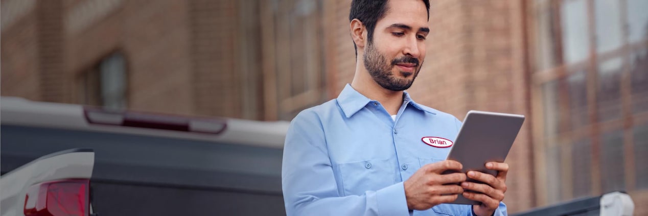 Close-up of a Man Using a Tablet Standing at the Back of a Truck