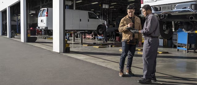 Two people talking in front of a GM repair shop