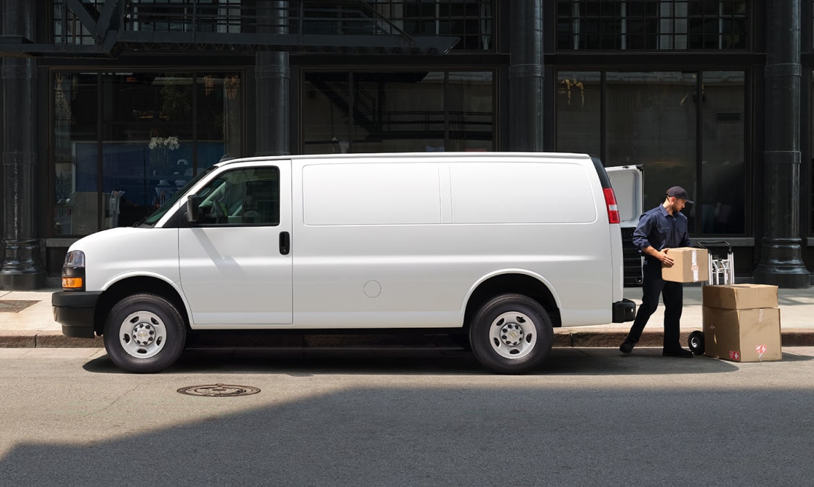 A worker unloading boxes from a white, unbranded electric van